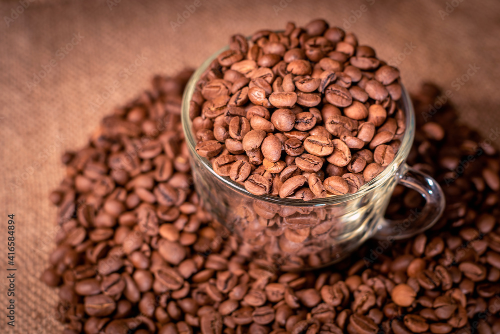 Roasted coffee beans with a glass coffee cup on a dark background Roasted coffee beans with a glass coffee cup on a dark background