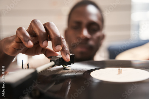 Man putting vinyl record in turntable while sitting on carpet photo