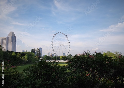 Scenic view of gigantic Ferris wheel seen faraway from across the park
