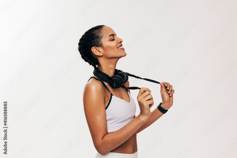 Side view of fitness woman standing on white background with closed eyes holding her dutch braids Side view of fitness woman standing on white background with closed eyes holding her dutch braids