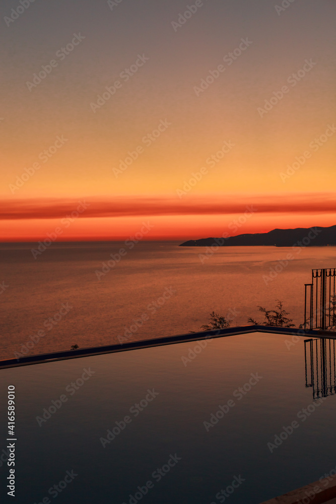 Sunset over sea with reflection from water in the swimming infinity pool at the evening. Relax at the end of the day. Colorful view.