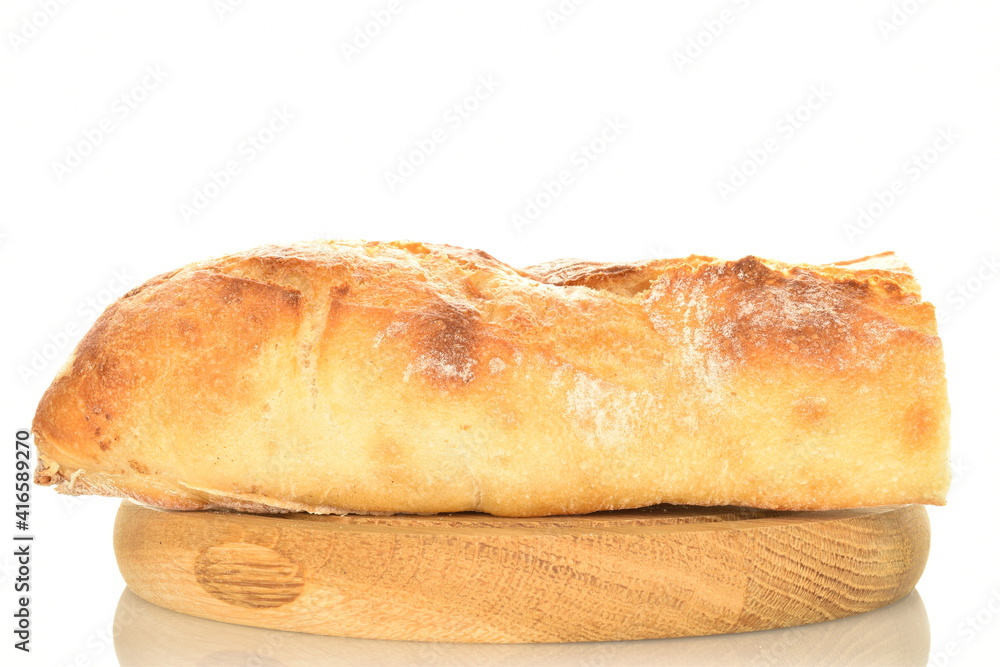 One half of delicious freshly baked French baguette on a round wooden tray, close-up, isolated on white.