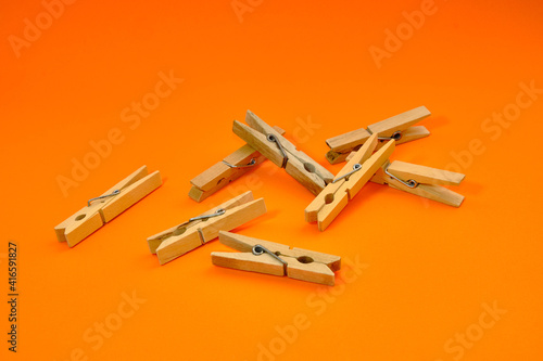 Set of wooden clothespins that appear one by one on an orange background.  © Fernando