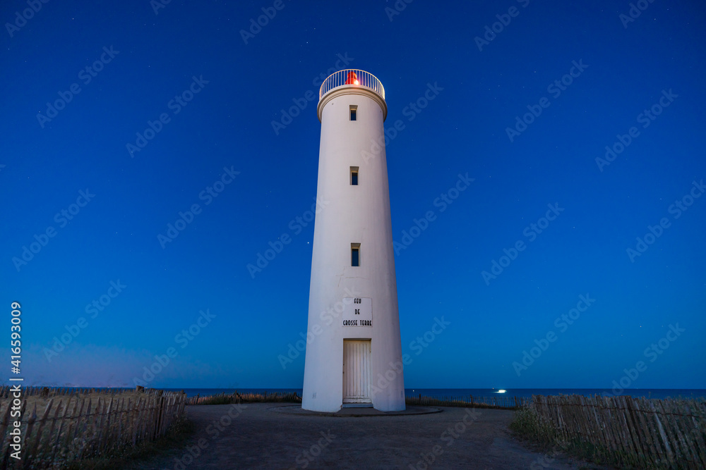 Beautiful lighthouse on the French west coast during blue hour in the sunrise at summertime with a blue sky without any cloud. The inscription 