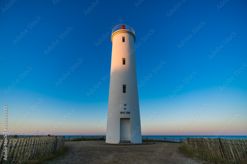 Beautiful lighthouse on the French west coast during the sunrise at summertime and during a warm morning with a blue sky without any cloud. The inscription 