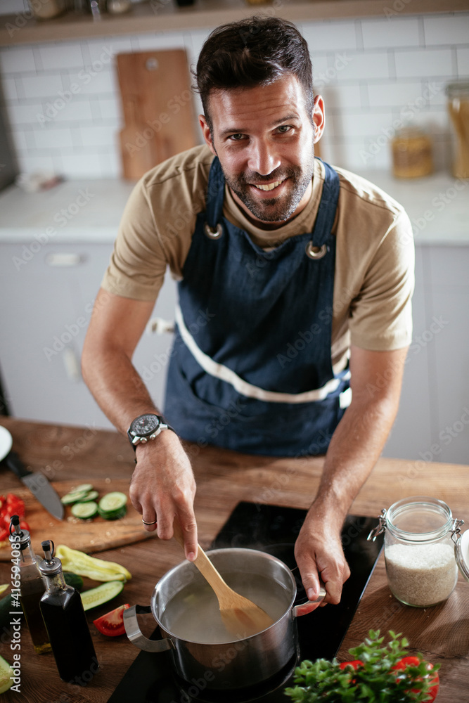 Handsome man preparing pasta in the kitchen. Guy cooking a tasty meal. Handsome man preparing pasta in the kitchen. Guy cooking a tasty meal.