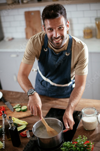 Handsome man preparing pasta in the kitchen. Guy cooking a tasty meal.