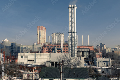 Combined heat and power plant. Smoke from the chimneys of a large factory. Large steam pipes of a working plant