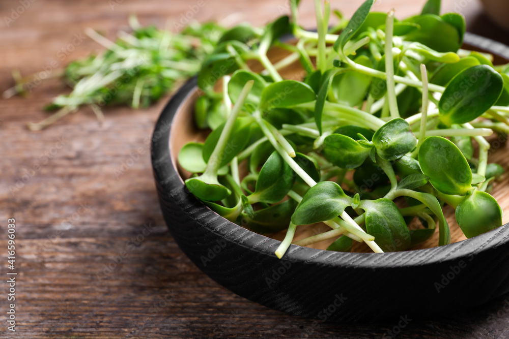 Bowl with fresh microgreen on wooden table, closeup Bowl with fresh microgreen on wooden table, closeup