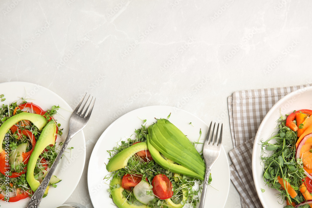Delicious vegetable salads with avocado and microgreen served on light table, flat lay. Space for text Delicious vegetable salads with avocado and microgreen served on light table, flat lay. Space for text
