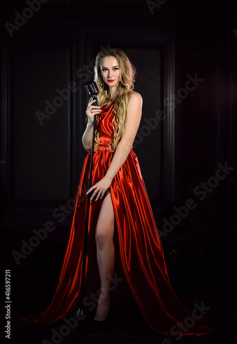 Singer in a red dress performs a song on stage in a microphone