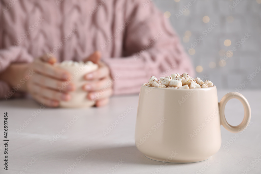 Cup of delicious hot cocoa with marshmallows on white table, space for text