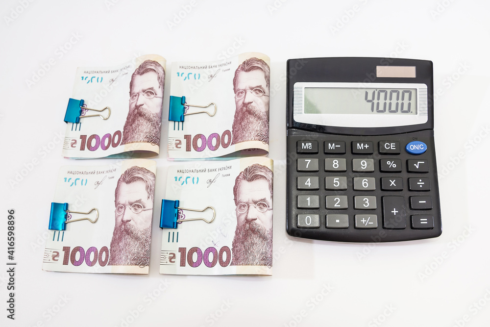 calculator and 1000 hryvnia fastened by a clip on white. calculator and 1000 hryvnia fastened by a clip on white.