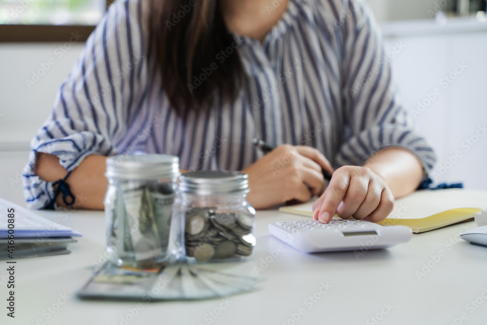 Growing savings concept. Saving money by hand puting coins money banknotes in jug glass financial accounting planning. Growing savings concept. Saving money by hand puting coins money banknotes in jug glass financial accounting planning.