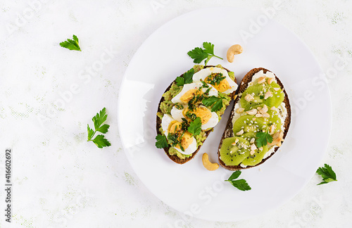 Vegetarian breakfast. Sandwich with avocado puree, boiled eggs and sandwich cream cheese, kiwi, nuts.  Healthy breakfast or lunch. Top view, overhead
