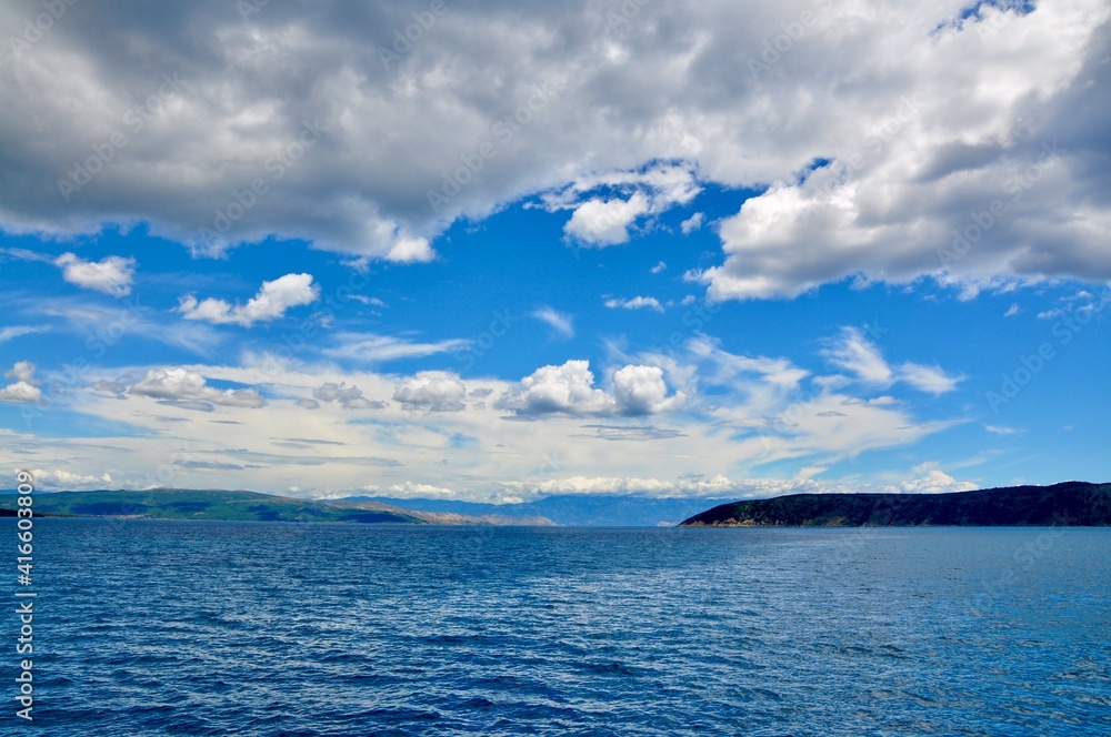 Scenic sky with beautiful white clouds. Panoramic view of the sea passage between the island and the mainland.