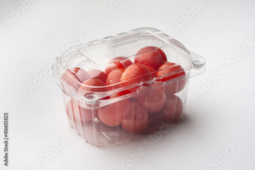 The cherry tomatoes with a transparent plastic bag. Red small tomatoes in a package on a white background.