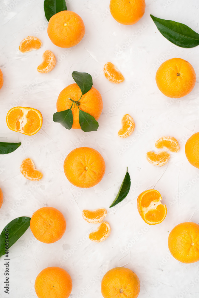 Obraz premium Tangerines: whole, cut and lobules with leaves on white table. Fruit contains many vitamins that are beneficial for healthy lifestyle. Close-up