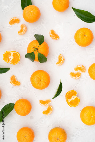 Tangerines  whole  cut and lobules with leaves on white table. Fruit contains many vitamins that are beneficial for healthy lifestyle. Close-up