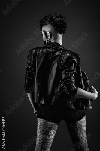 Fototapeta Naklejka Na Ścianę i Meble -  Attractive young woman from back, with punk hairstyle, wearing leather jacket and fishnet stockings
