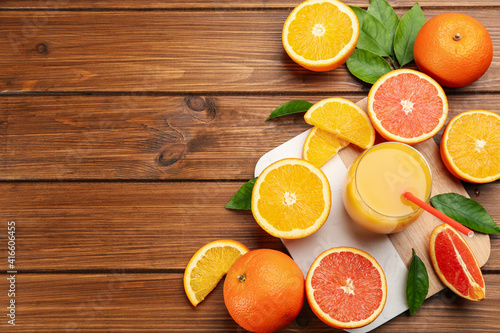 Delicious orange juice and fresh fruits on wooden table, flat lay. Space for text