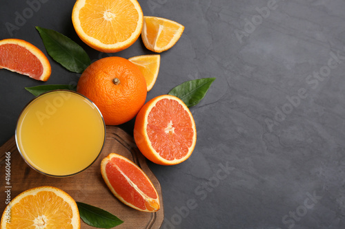 Delicious orange juice and fresh fruits on black table, flat lay. Space for text
