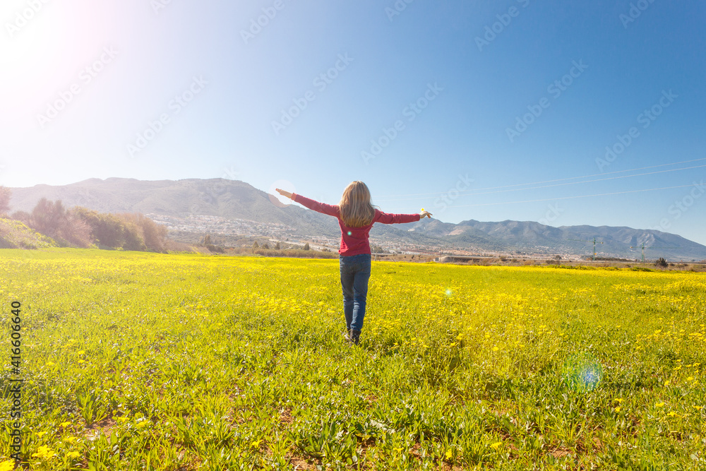 Concepto de una niña de espaldas corriendo por el campo lleno de flores amarillas. Concepto de una niña de espaldas corriendo por el campo lleno de flores amarillas.