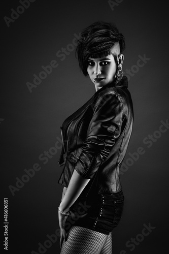 Attractive young woman from profile, with punk hairstyle, wearing leather jacket and fishnet stockings