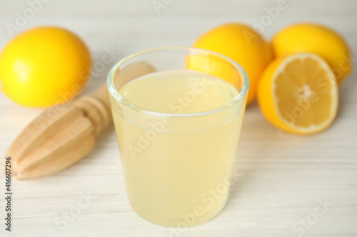 Freshly squeezed juice, lemons and reamer on white wooden table