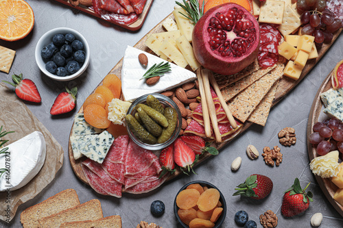 Wooden plates with different delicious snacks on grey table, flat lay