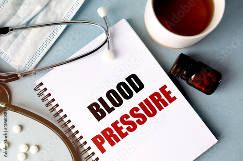 Inscription - BLOOD PRESSURE. Written in a notepad to remind you of what's important. Top view of the table along with a stethoscope and a mask. Health care concept.