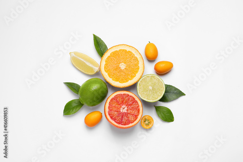 Fresh juicy citrus fruits with green leaves on light background, flat lay