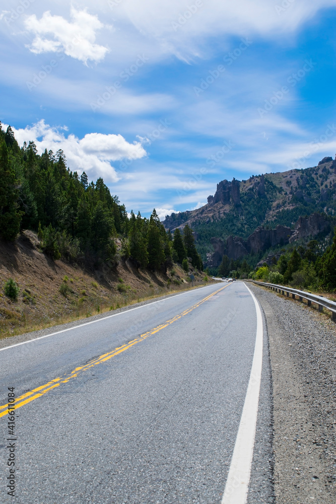 Ruta entre montañas y vegetación, con un cielo de nubes vistosas Ruta entre montañas y vegetación, con un cielo de nubes vistosas