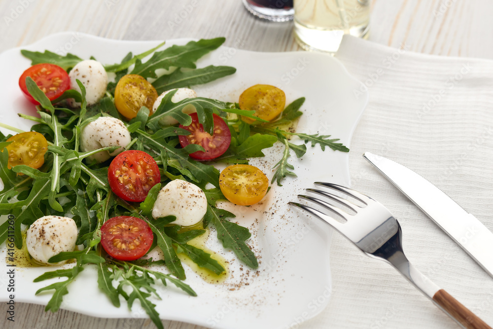 Dietary salad with mozzarella cheese, cherry tomatoes and arugula.