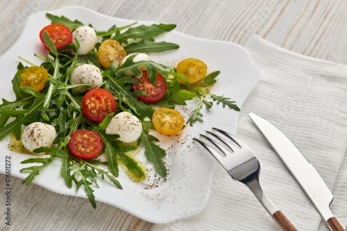 Dietary salad with mozzarella cheese, cherry tomatoes and arugula.