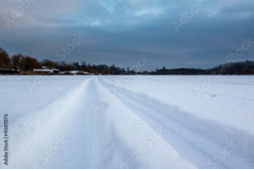 Cross-country wild ski track lines on snow going forward in evening with epic cloudy sky. Active sport recreation in winter