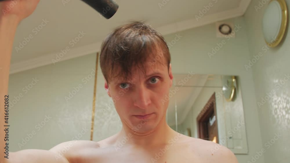 Man dries hair in the bathroom Man dries hair in the bathroom