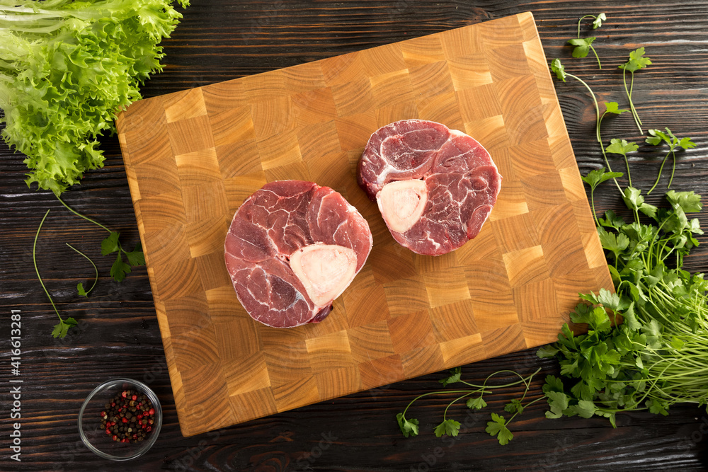 Raw piece of beef with herbs on a cutting board.