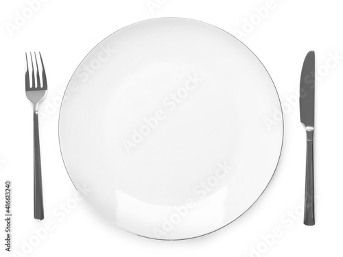 Plate and cutlery on white background, top view