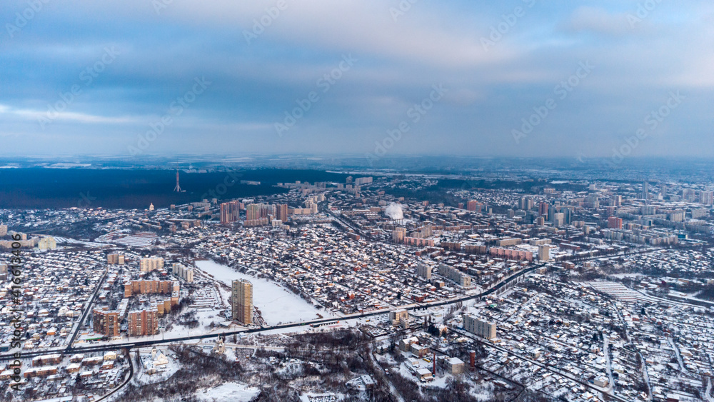 Aerial high view Kharkiv city Shevchenkivskyi district in snow with urban and residential multistorey buildings with scenic colorful cloudy sky in winter