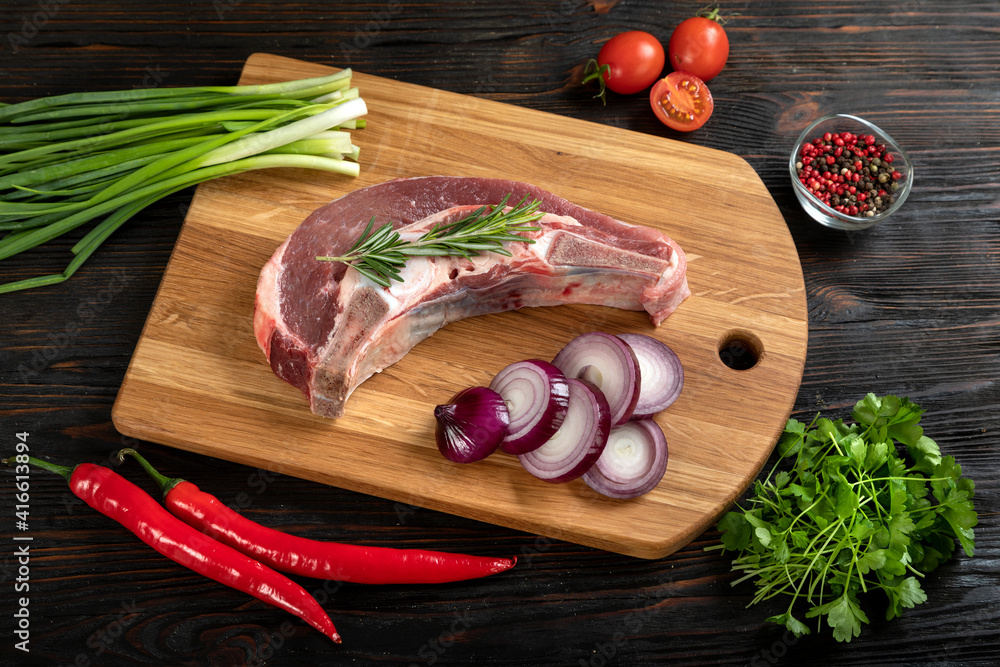 Raw piece of beef with herbs on a cutting board.