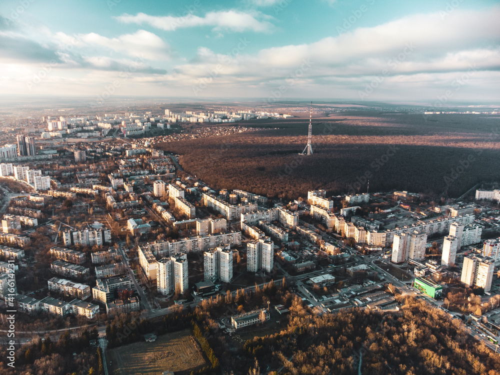 Aerial view Kharkiv city center and Pavlove Pole districts. Multistorey buildings near forest with telecommunication tower antenna with scenic bright sky in winter