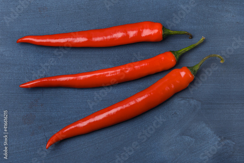 Three red chili peppers on a blue background
