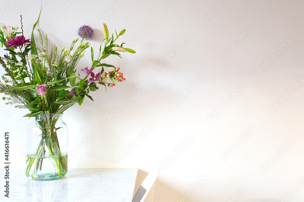 Beautiful spring flowers in glass vase on white table near white wall copy space modern interior decoration, Easter flowers background colorful design Beautiful spring flowers in glass vase on white table near white wall copy space modern interior decoration, Easter flowers background colorful design