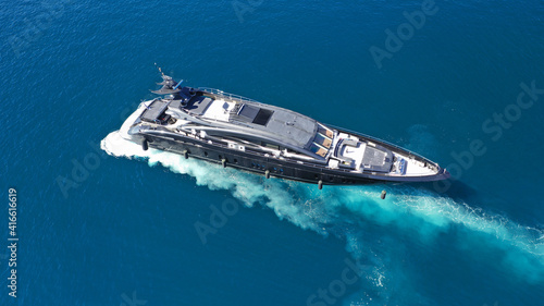 Aerial drone photo of modern yacht preparing to speed in Mediterranean port with deep blue sea