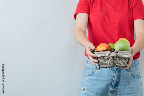 A person holding a fruit basket in the hand