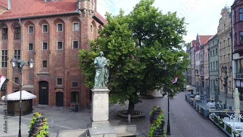 Rynek Staromiejski In Toruń, Poland, with the Town Hall and the statue of Nicolaus Copernicus in the foreground. In the distance, a panorama of Toruń with tenement houses and the Vistula River.