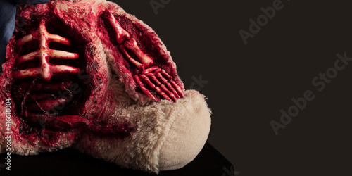 bear on a gray background close-up with a skeletonized hand and a torn abdomen covered in blood. halloween concept. horror toy