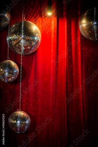design of a photo zone for guests - mirror disco balls against the background of a red velvet curtain.