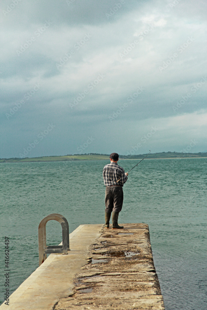 Irish fisherman fishing in front of the north sea on a cloudy day. Irish fisherman fishing in front of the north sea on a cloudy day.
